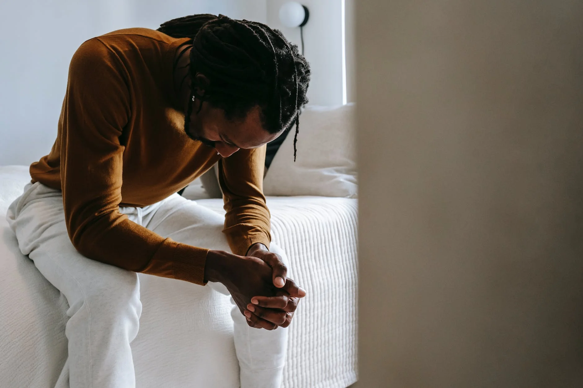 Why Am I Here Just To Suffer: Understanding the Purpose of Pain and Suffering 1 desperate black man sitting on bed in deep thoughts